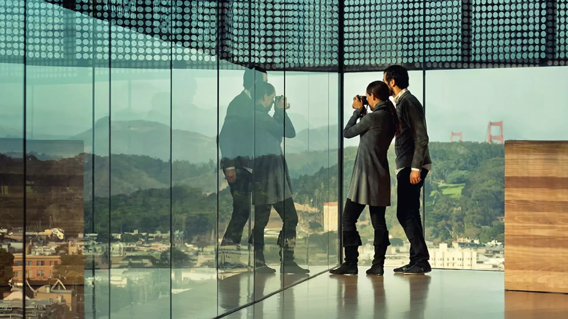 在贝博体彩app的德扬博物馆，两个人透过玻璃墙凝视。.