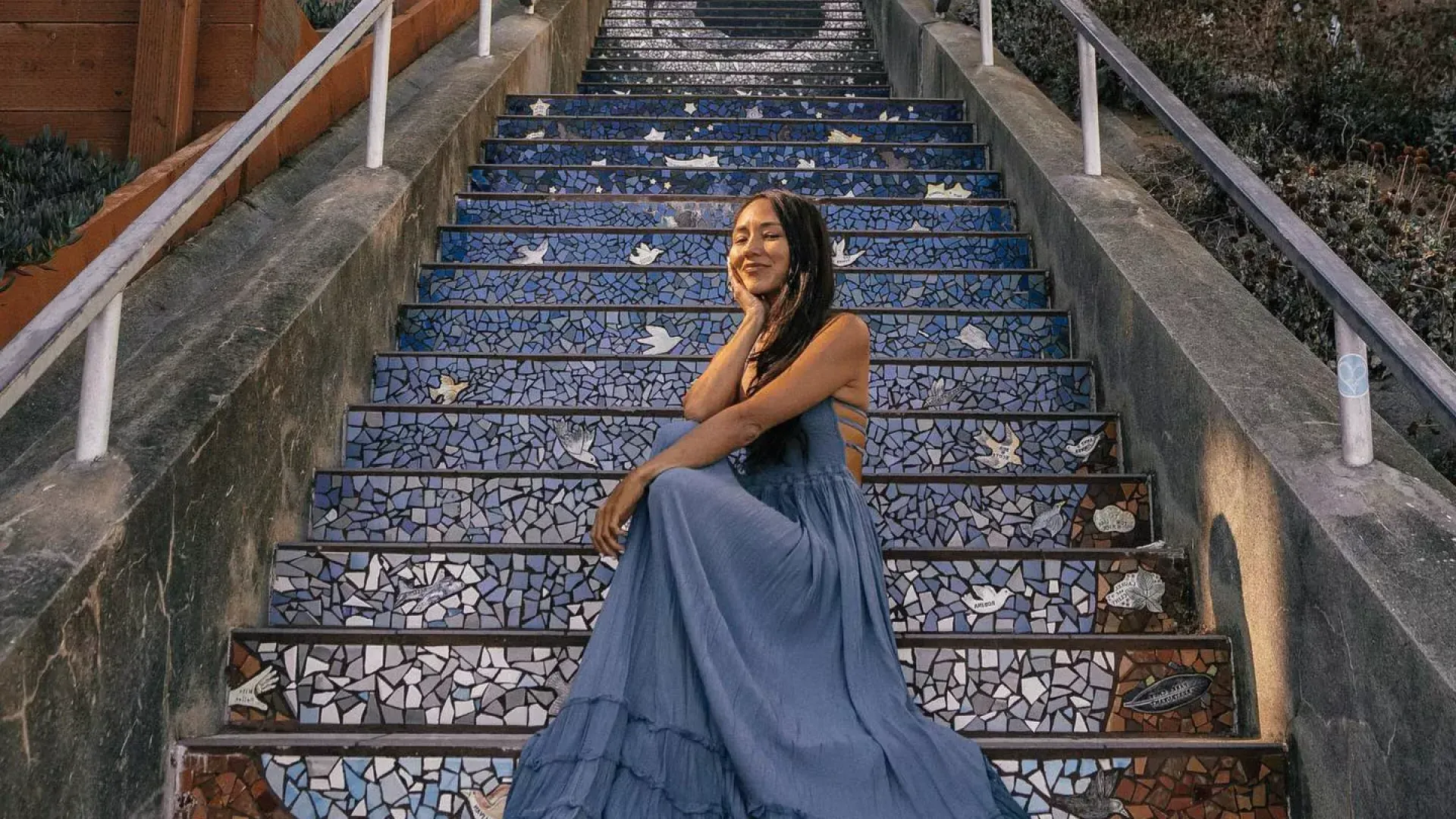 一名妇女坐在贝博体彩app日落社区第16大道的瓷砖楼梯上拍照.