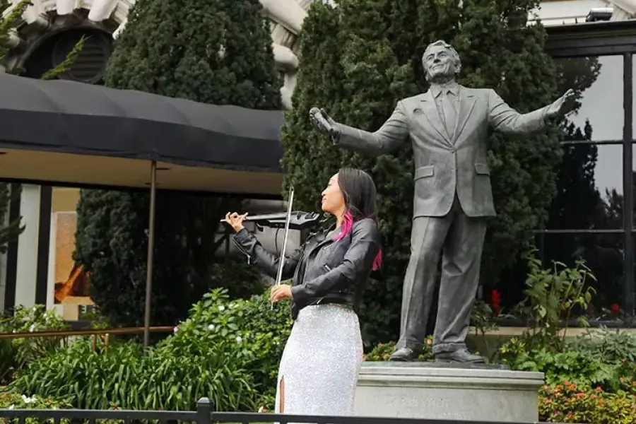 一名妇女在费尔蒙酒店的托尼·班尼特雕像前拉小提琴.