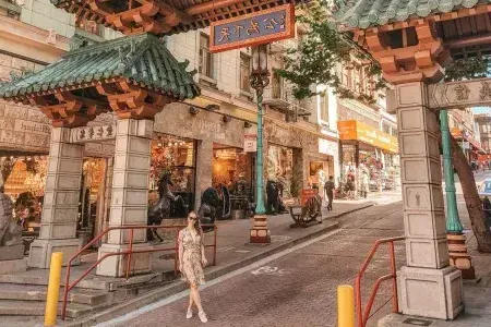 一名女子在装饰华丽的大门前摆姿势。, 标志着贝博体彩app唐人街的入口.